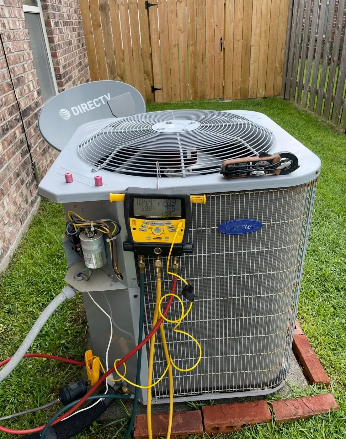 Carrier air conditioner condenser being serviced with refrigerant gauges in a Houma Louisiana yard
